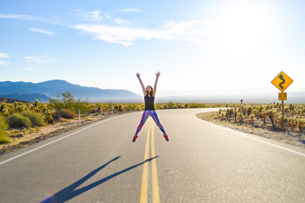 Meet Clumsy Traveler Rachel; girl jumping in the middle of the road Joshua Tree
