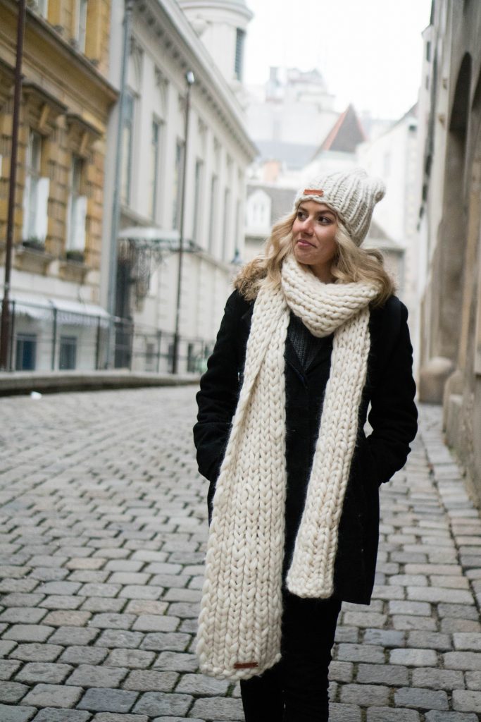 I'm Still The Clumsiest Traveler Ever; Girl walking through European city with white knit beanie and white knit scarf