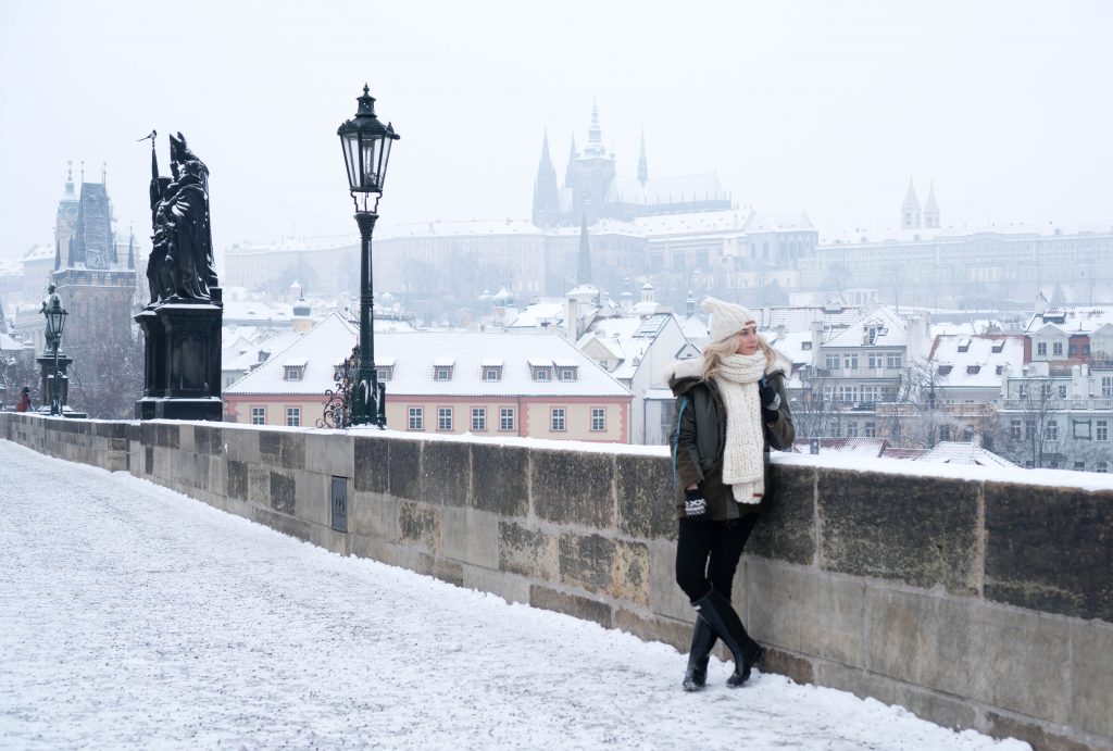 Winter Wonderland Lookbook; blonde girl on Charles Bridge Prague chunky knit scarf and beanie snow