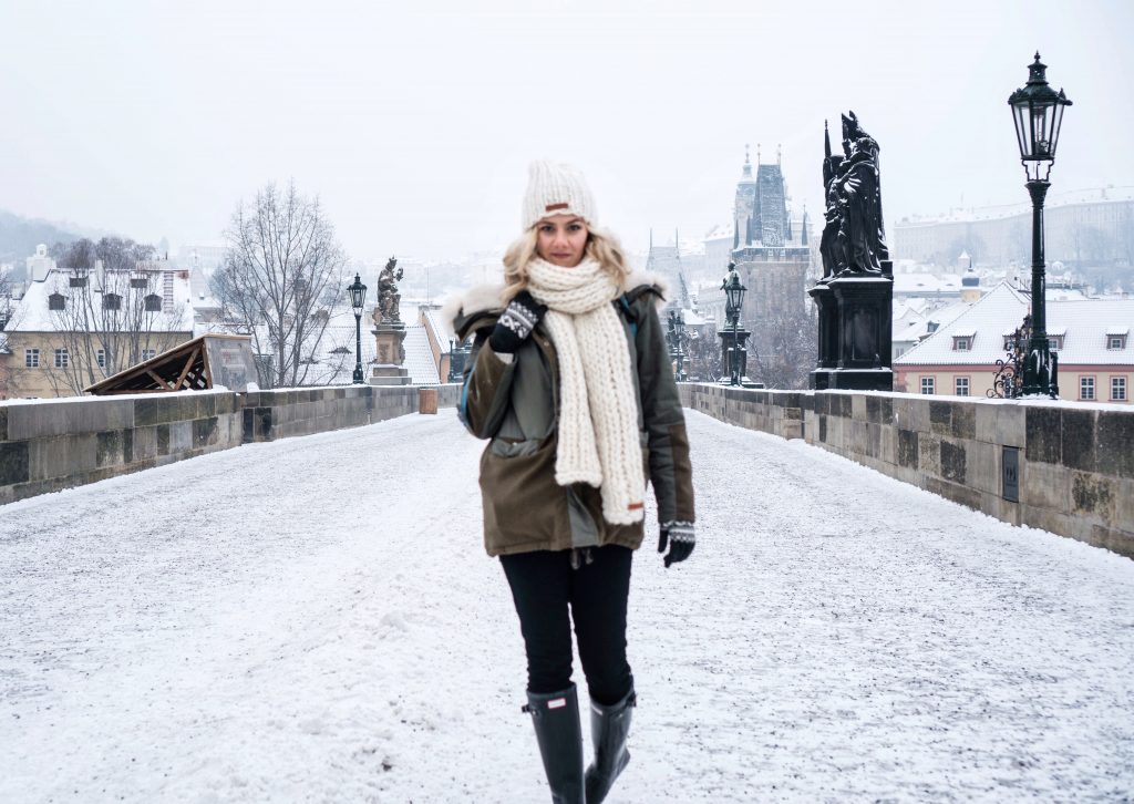 Winter Wonderland Lookbook; blonde girl on Charles Bridge Prague chunky knit scarf and beanie snow