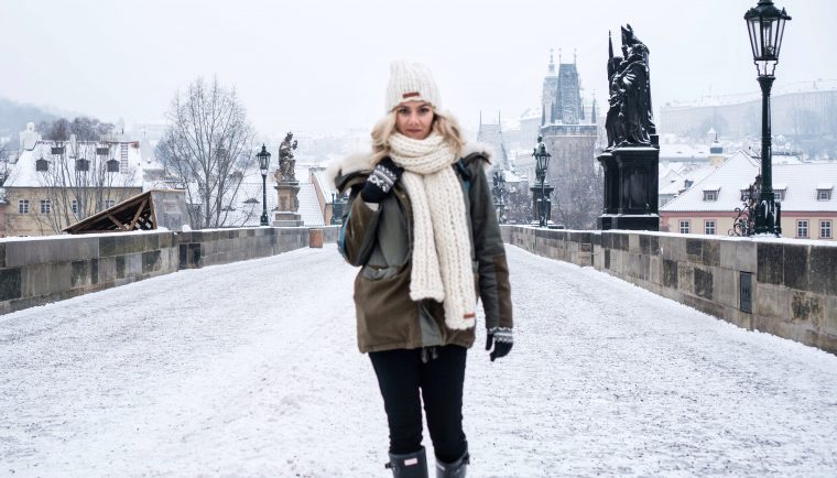 Winter Wonderland Lookbook; blonde girl on Charles Bridge Prague chunky knit scarf and beanie snow