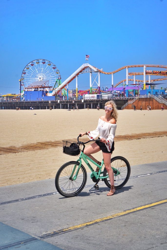 travel and reduce your carbon footprint; girl on bike santa monica pier