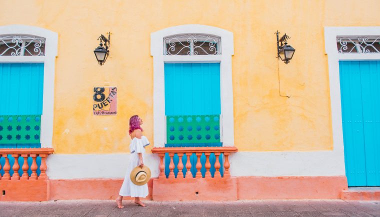24 Hours in Santo Domingo; girl walking in front of yellow wall