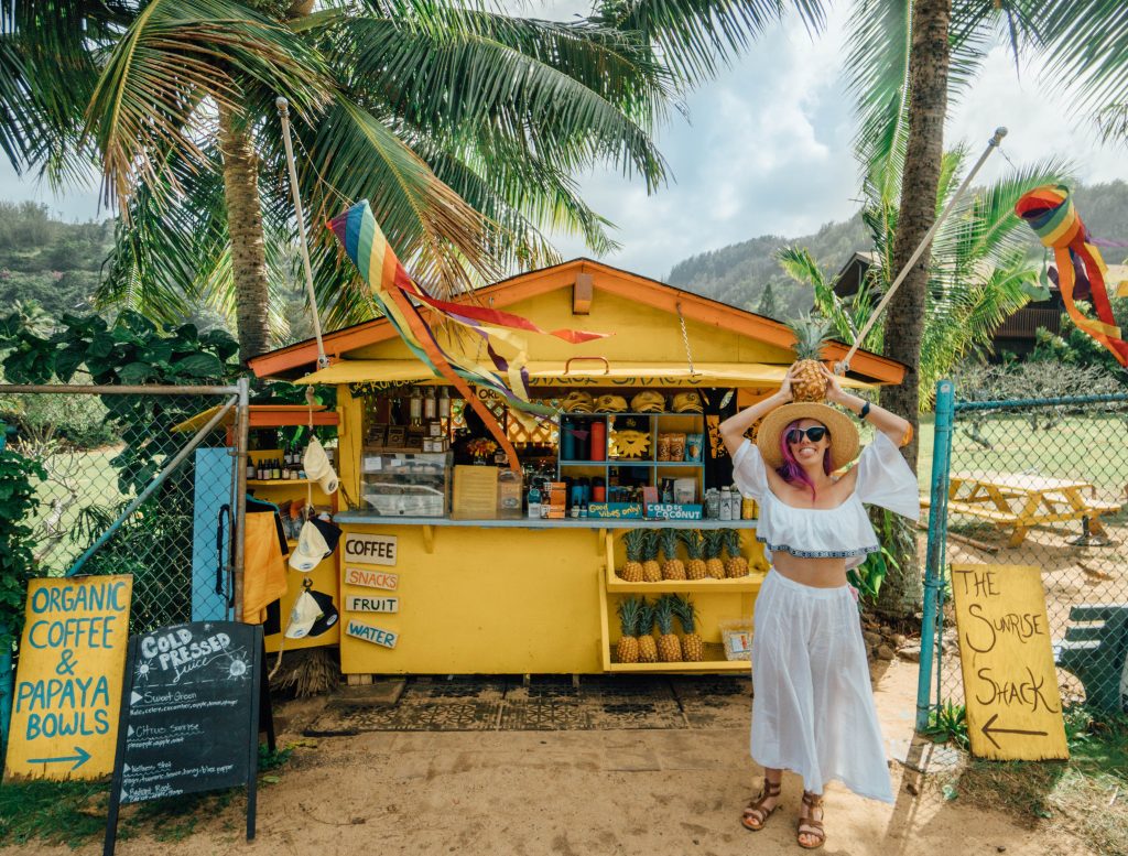 best things to do in Oahu; girl with pineapple at the Sunrise Shack yellow north shore