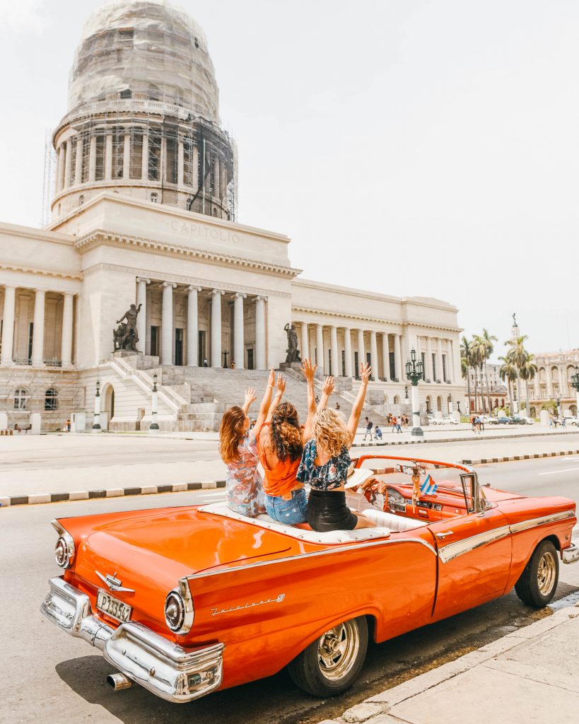 havana cuba photography; girls in red old convertible in parque central with el capitolio in the background