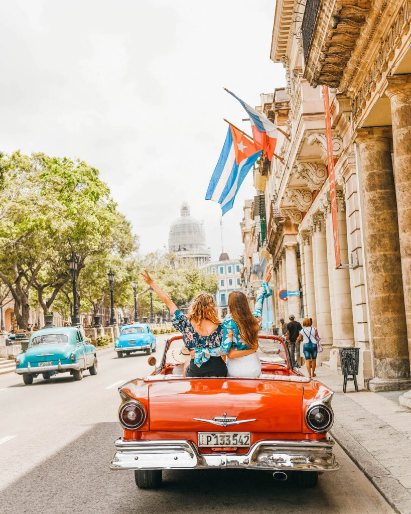 havana cuba photography; girls in red old convertible in parque central with el capitolio in the background