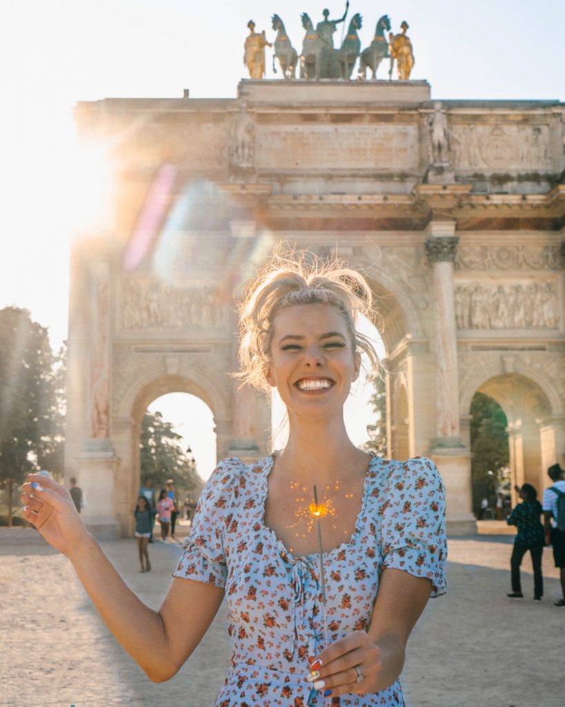 Thanks to the Instagram Algorithm, I Learned 5 Important Lessons; blonde girl with sparkler in front of Louvre Arch in Paris France Bastille Day